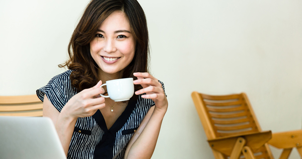 仕事中にコーヒーを飲む笑顔の女性