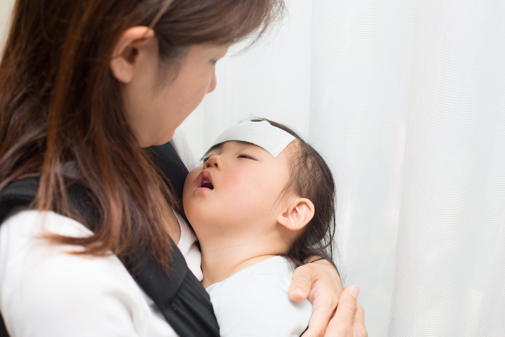 熱を出してぐったりする子供を抱いたお母さん