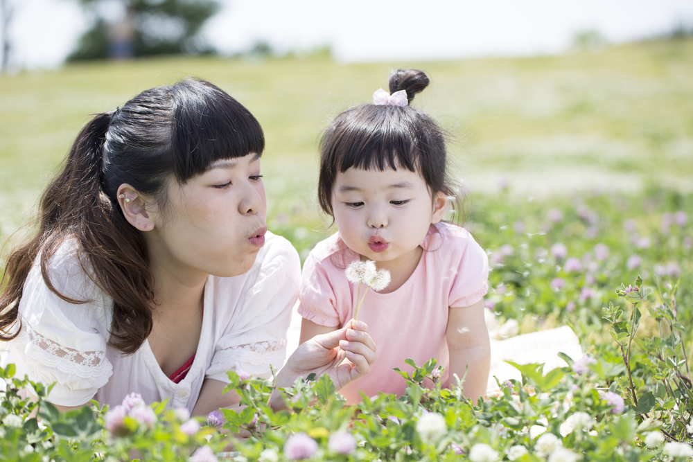 たんぽぽの綿毛を吹く母娘