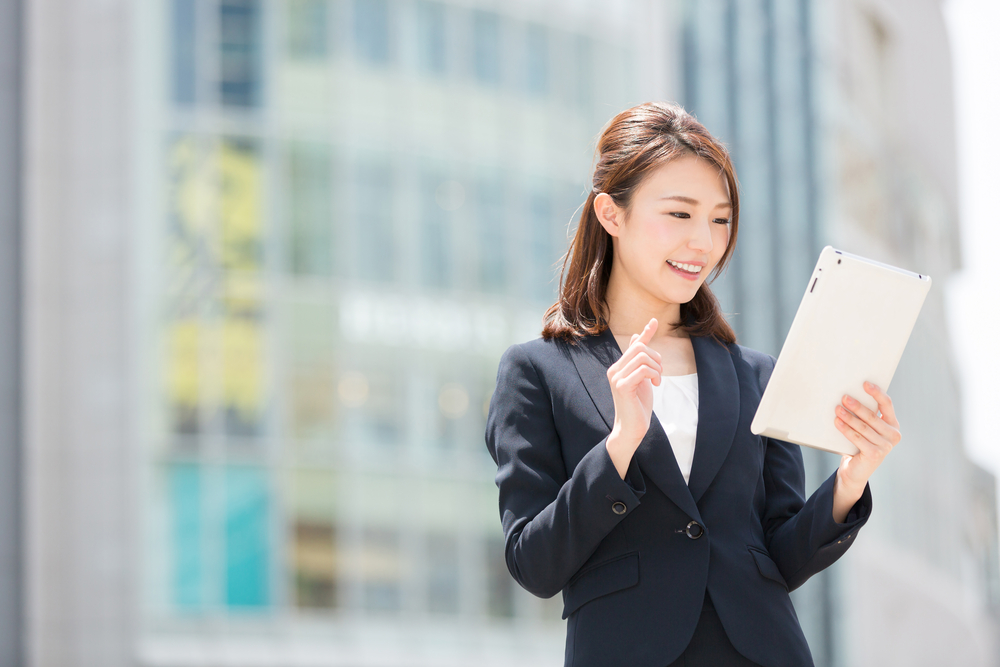 職場の前で書類を見て喜ぶ女性